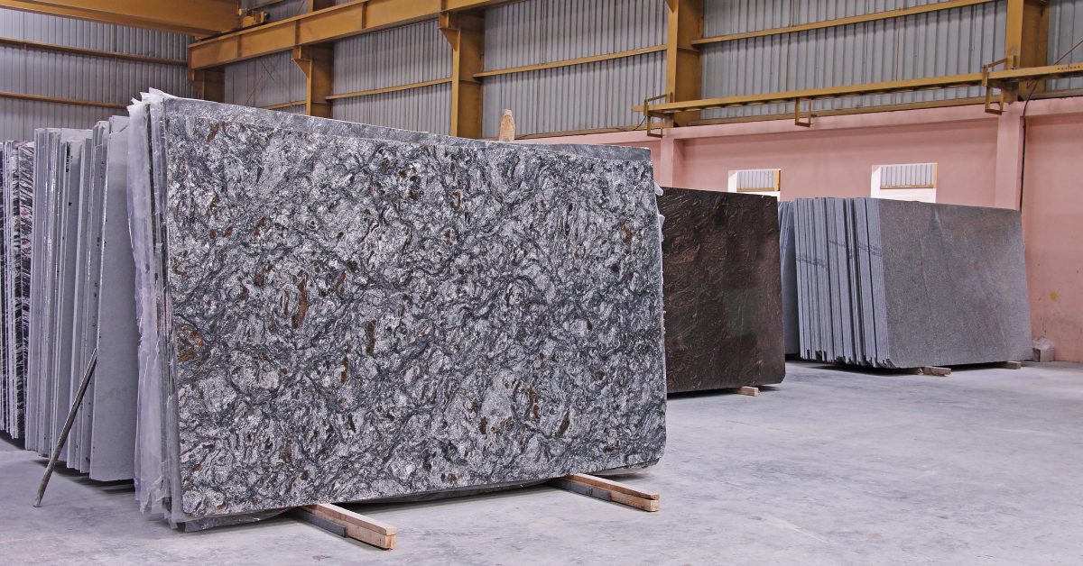 An industrial storage warehouse with various polished stone slabs stacked together on wooden displays.