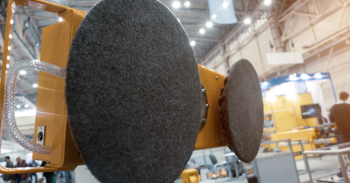 A close-up of a yellow and black vacuum grip lifter for wood and stone slabs in an industrial warehouse.