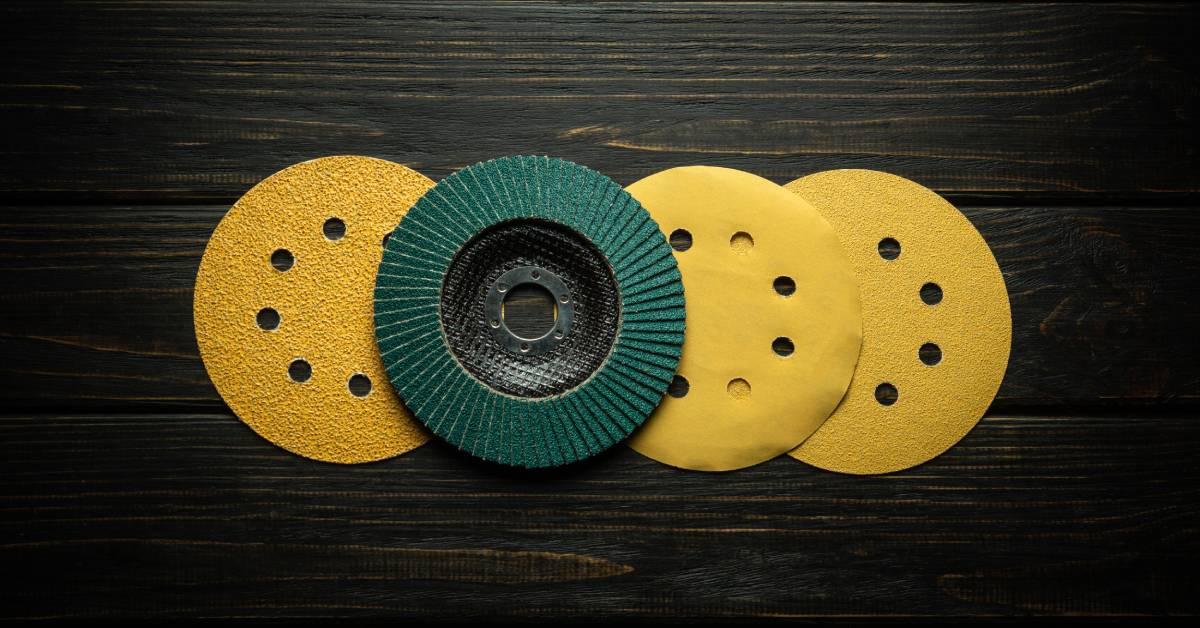 A series of yellow and green professional stone polishing pads arranged together on a dark wooden table.