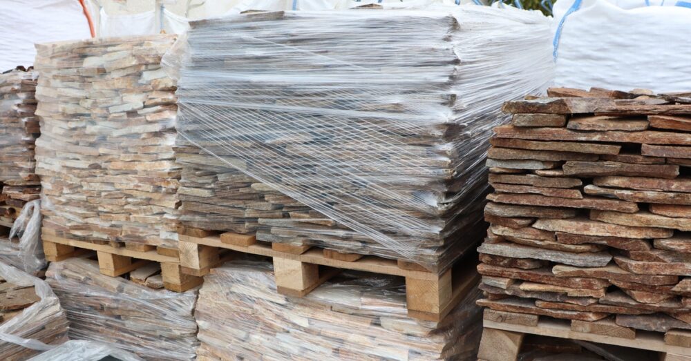 A close-up of different-colored stacked stone pallets that are wrapped with packaging film for storage solutions.