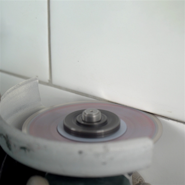 Professional tile installer using Distar Cleaner blade for grout removal